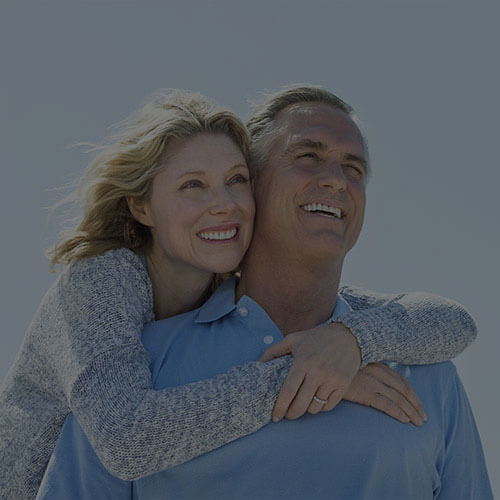 A couple smiling together while her hands are around the man’s shoulders